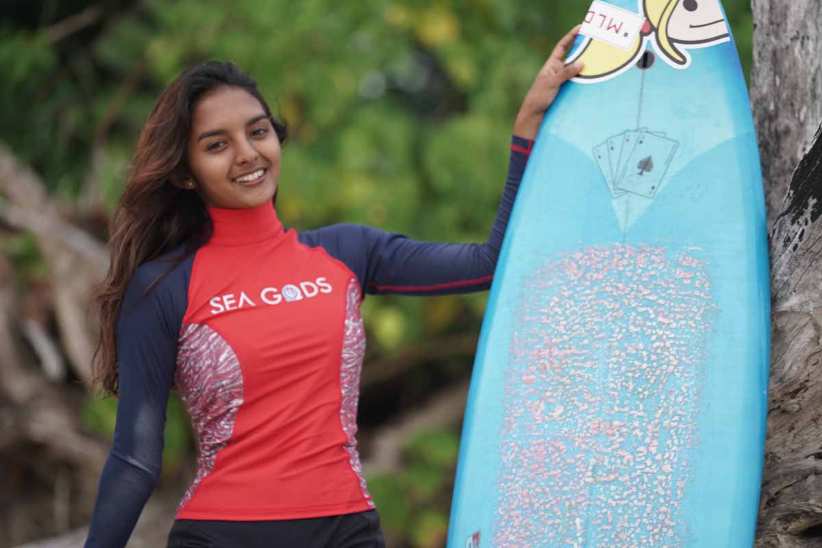Salini tersenyum dengan memegang papan surf miliknya
